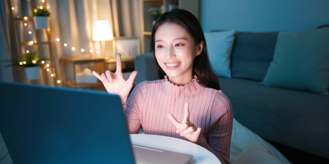 woman with love sign language in front of screen